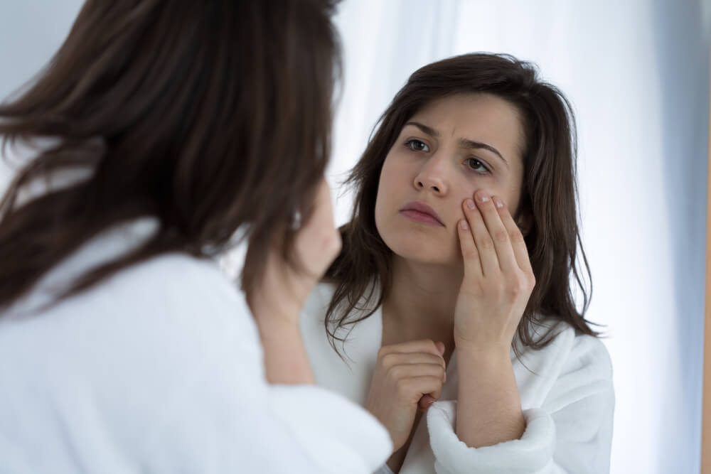 Woman looking at skin in mirror