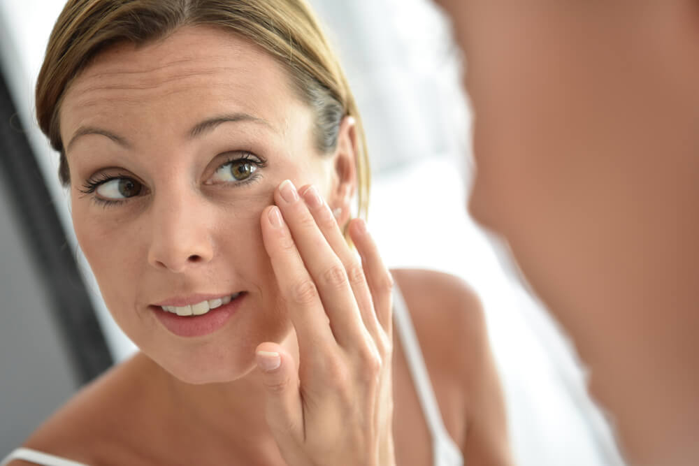 Woman looking at skin in mirror